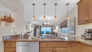 Une cuisine moderne avec des meubles en bois, un lave-vaisselle en acier inoxydable et des luminaires suspendus.