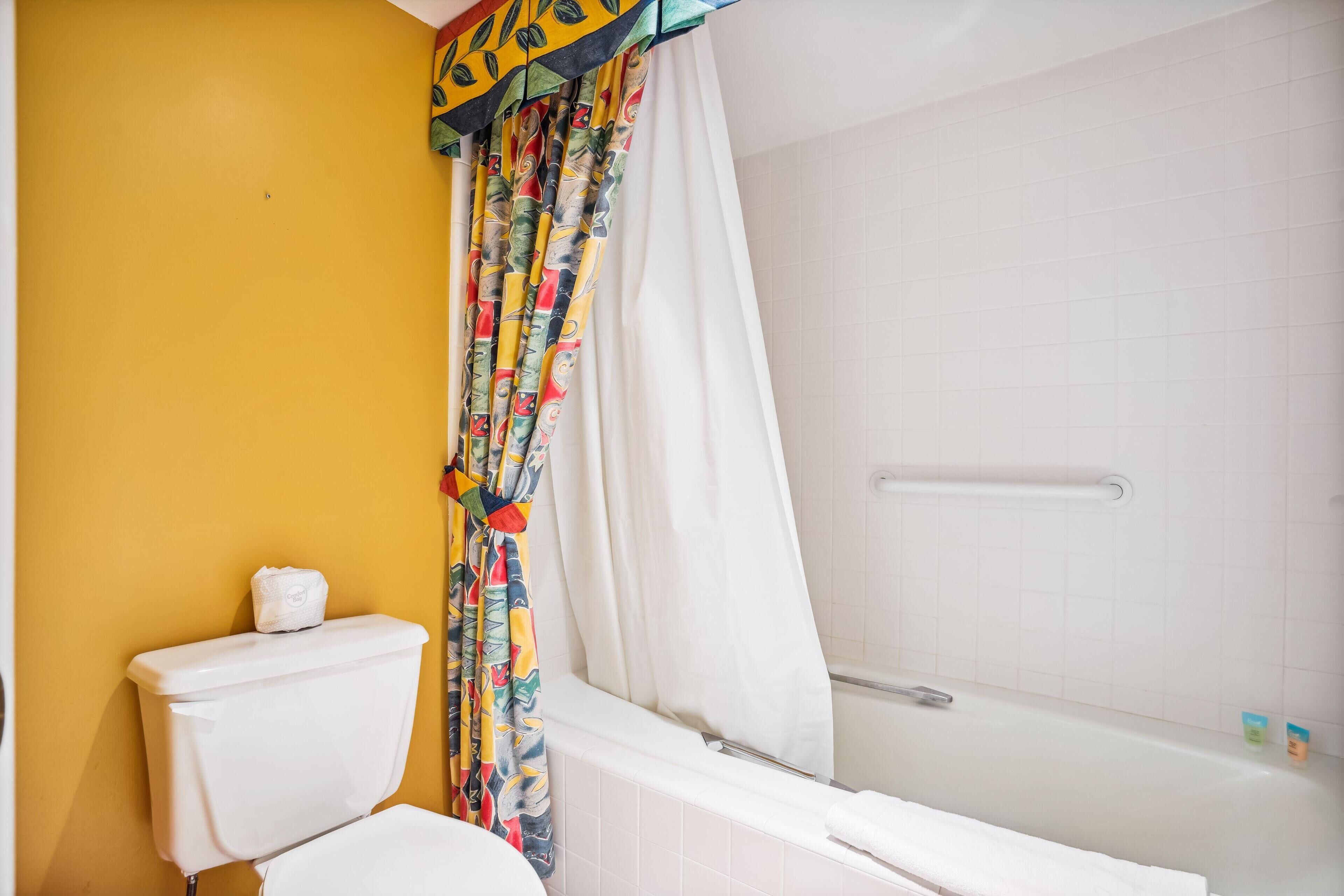 Une salle de bain équipée de toilettes, d’une baignoire et d’un rideau de douche.
