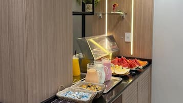 A buffet setup with various food items and a coffee machine.