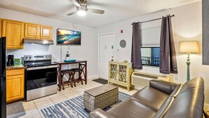 A compact living space with a kitchenette, a dining area, a seating area with a sofa, and a window with curtains.