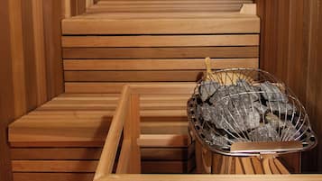Een houten sauna met banken en een metalen bak voor stenen.