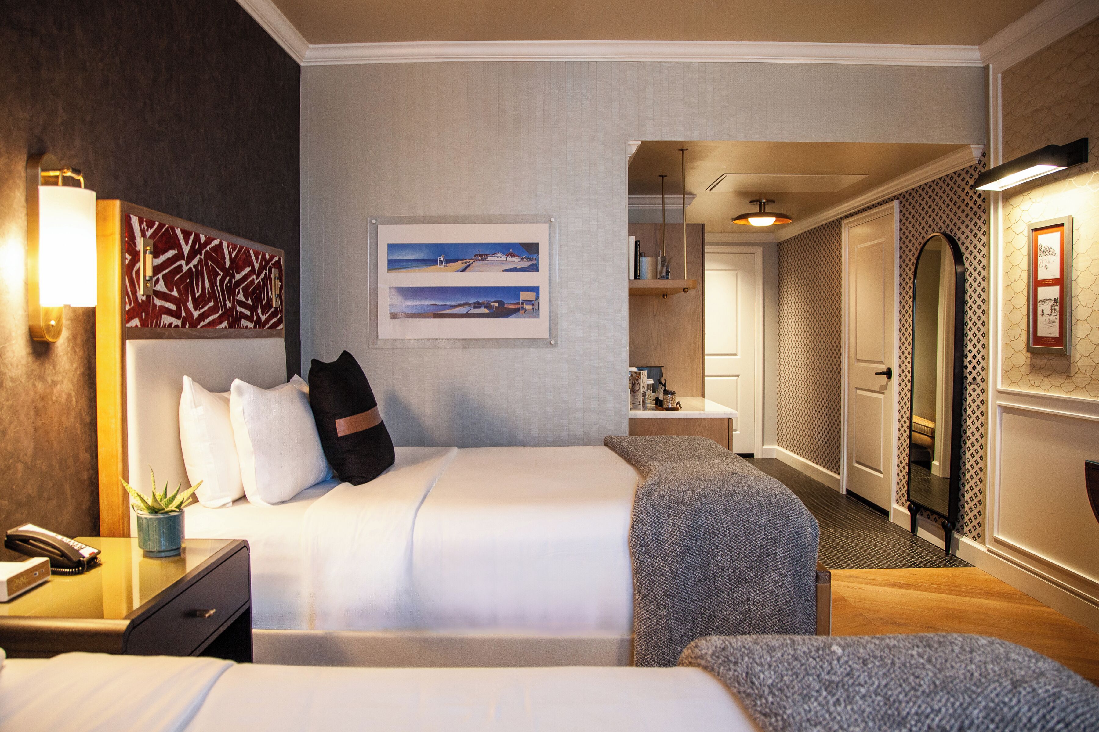 Ein Hotelzimmer mit Bett, Nachttisch, Lampe und einem gerahmten Bild an der Wand.