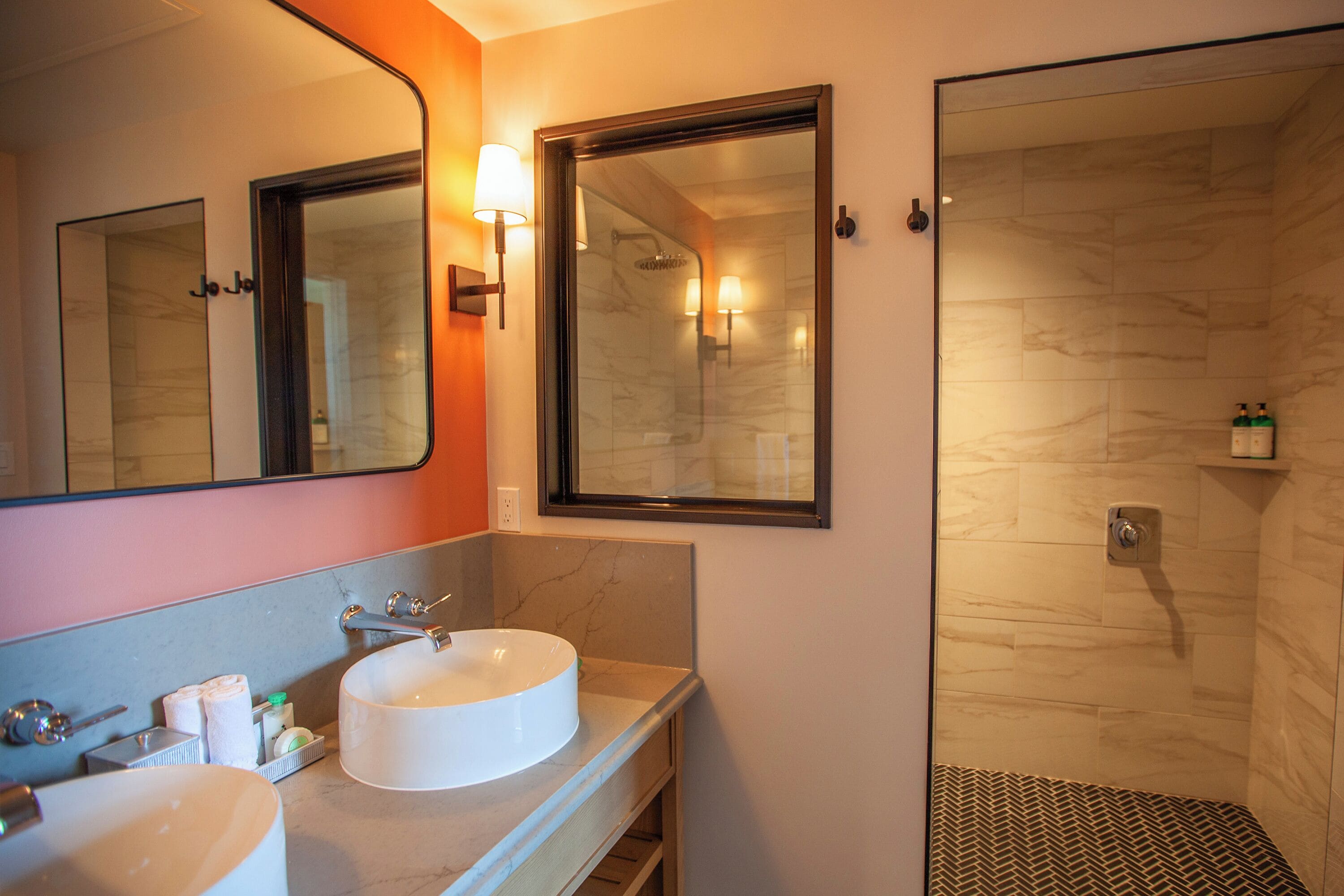 Une salle de bain moderne avec un grand miroir, deux lavabos et un espace douche.