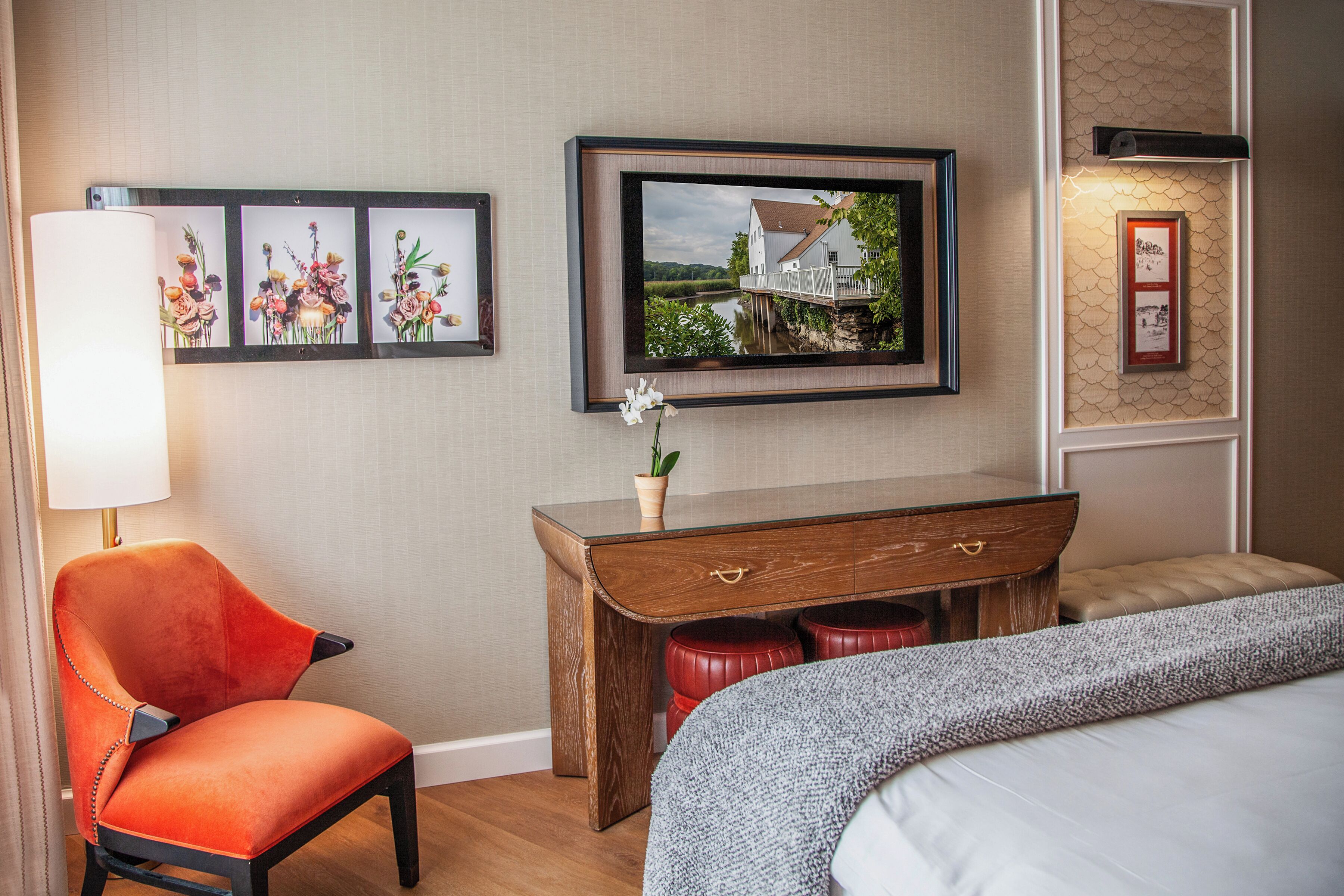 Een hotelkamer met een bed, een stoel, een houten dressoir en kunstwerken aan de muur.