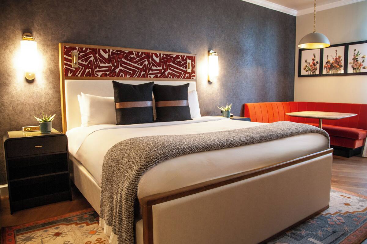Une chambre d’hôtel avec un grand lit, un canapé rouge, une petite table et un mur décoratif.