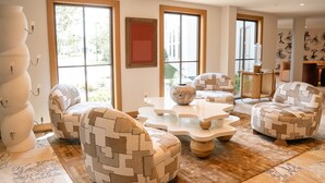Un salon moderne avec des meubles aux motifs géométriques, de grandes fenêtres et un design minimaliste.