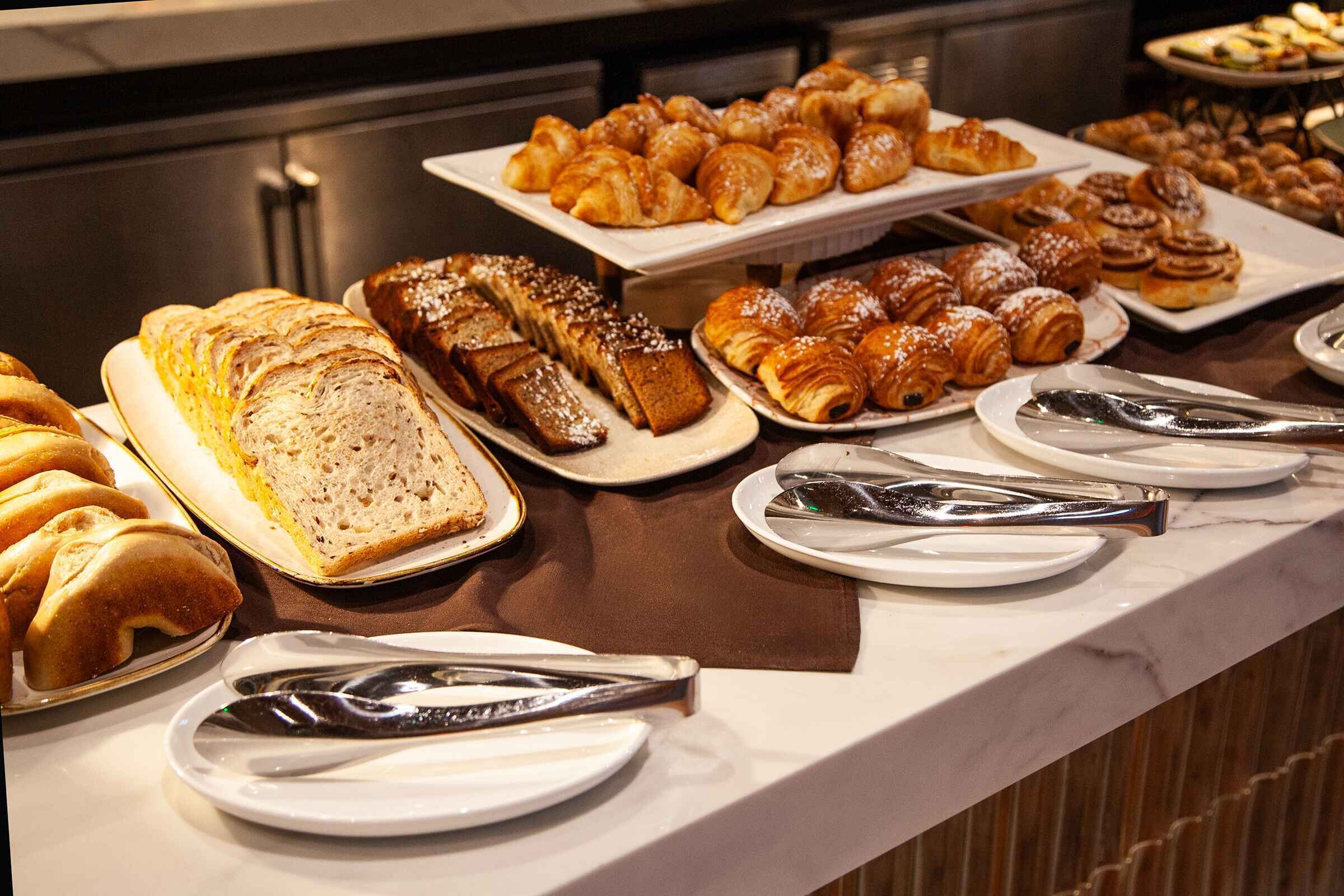 A buffet with various pastries and breads.