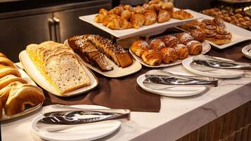 A buffet with various pastries and breads.