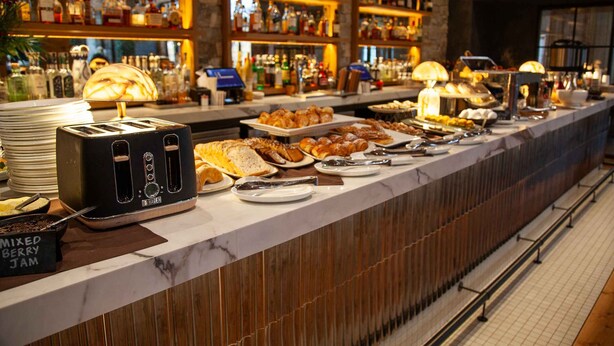 Un buffet proposant divers plats et, en arrière-plan, une sélection de bouteilles d’alcool.