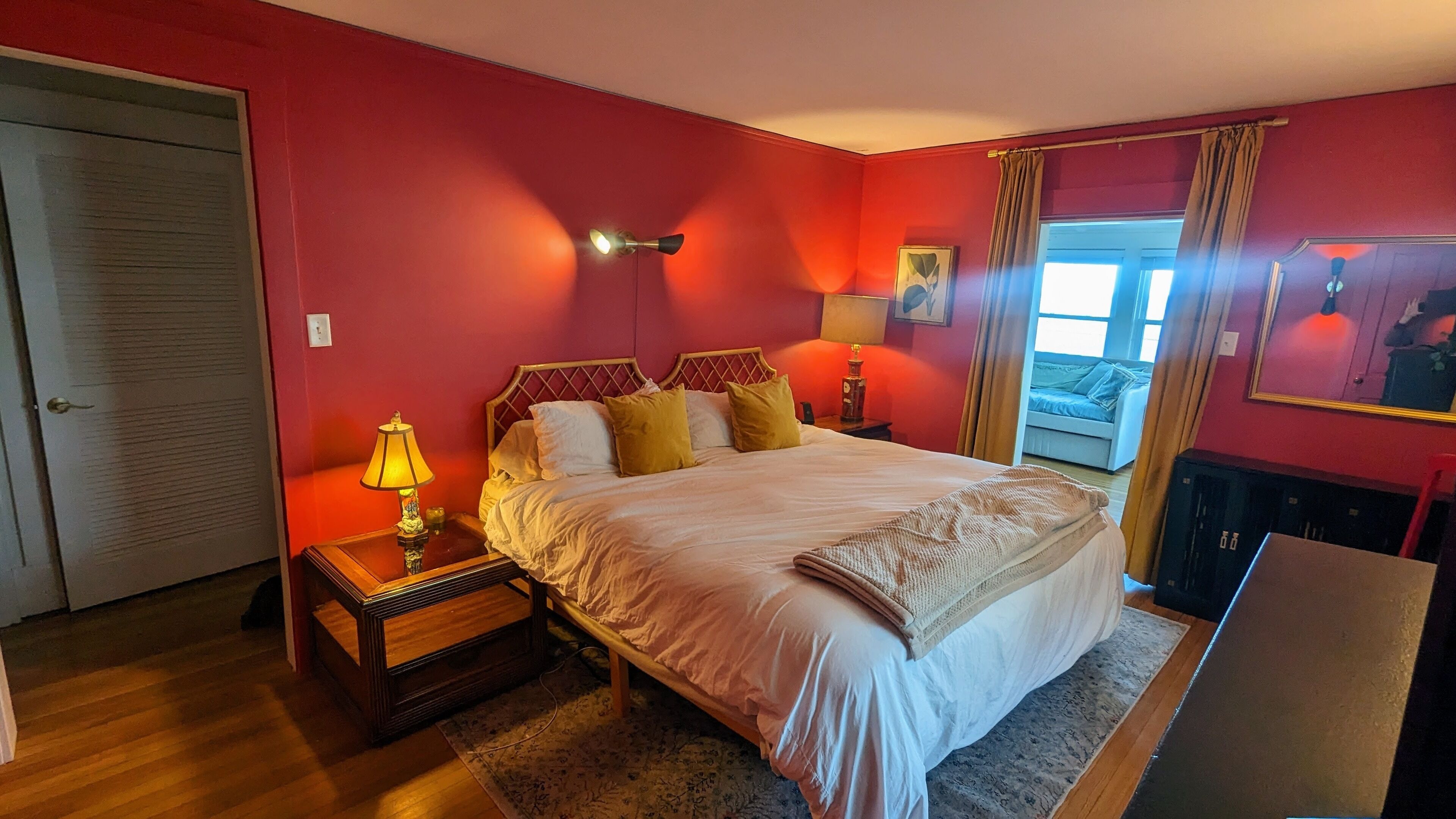 A bedroom with a bed, bedside tables, a lamp, a window with curtains, and a door.