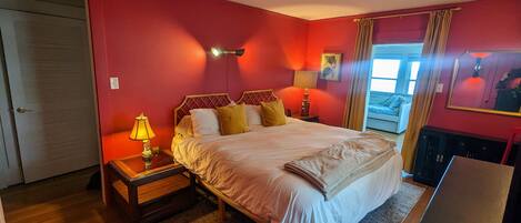 A bedroom with a bed, bedside tables, a lamp, a window with curtains, and a door.