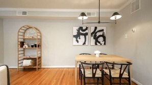 Un comedor con una mesa y sillas de madera, una lámpara colgante y arte abstracto en la pared.