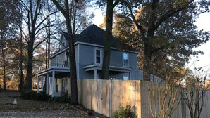 A two-story house with a front porch and a wooden fence. - The Alexandria House #1 (Jackson)