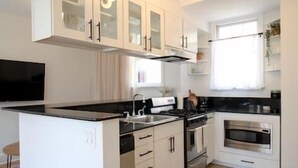 A modern kitchen with white cabinetry, a black countertop island, and stainless steel appliances. - Brand New 1bdr Rittenhouse Sq. Hosted By StayRafa (Philadelphia)