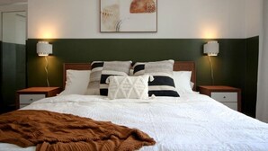 A neatly made bed with a brown throw blanket, two bedside tables with lamps, and a framed abstract artwork above the bed. - Brand New 1bdr Rittenhouse Sq. Hosted By StayRafa (Philadelphia)