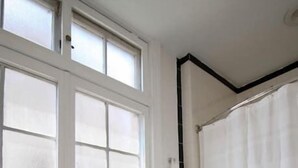 A bathroom with a large window, white tiled walls, a shower curtain, and a green mat. - Brand New 1bdr Rittenhouse Sq. Hosted By StayRafa (Philadelphia)