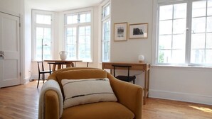 A room with a mustard-colored armchair, a wooden dining table with chairs, and large windows with white frames. - Brand New 1bdr Rittenhouse Sq. Hosted By StayRafa (Philadelphia)