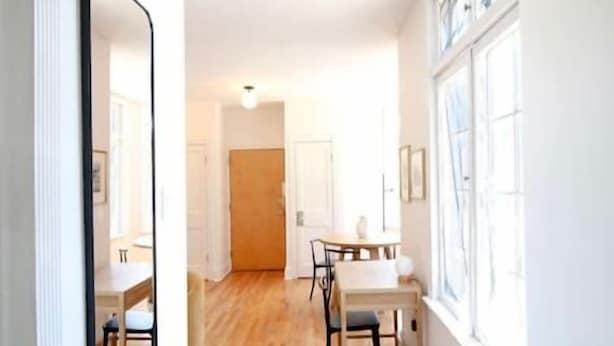 A hallway with wooden flooring, white walls, a dining area with a table and chairs, and a large window on the right. - Brand New 1bdr Rittenhouse Sq. Hosted By StayRafa (Philadelphia)