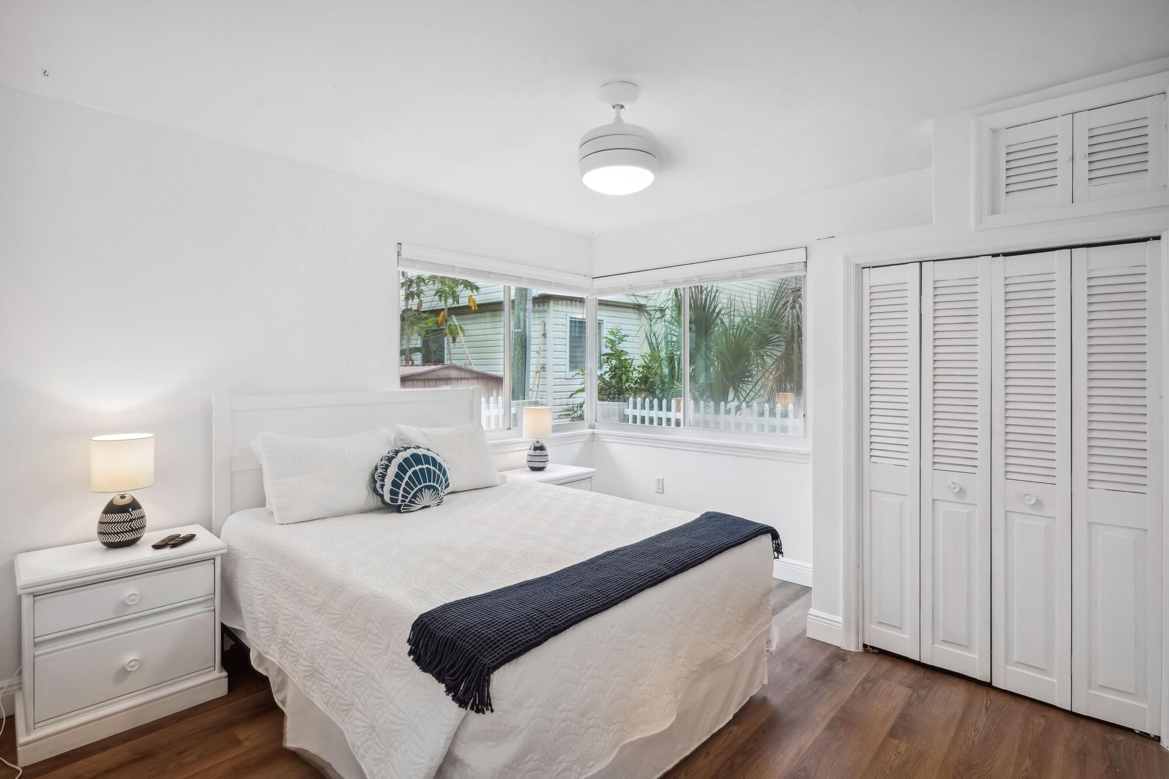 Une chambre à coucher avec un lit, des tables de chevet, une fenêtre et une armoire.