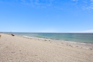 A beach with a cross in the distance, a clear sky, and calm water. - Beach Livin 1 - 1 Bedroom Downstairs (Treasure Island)
