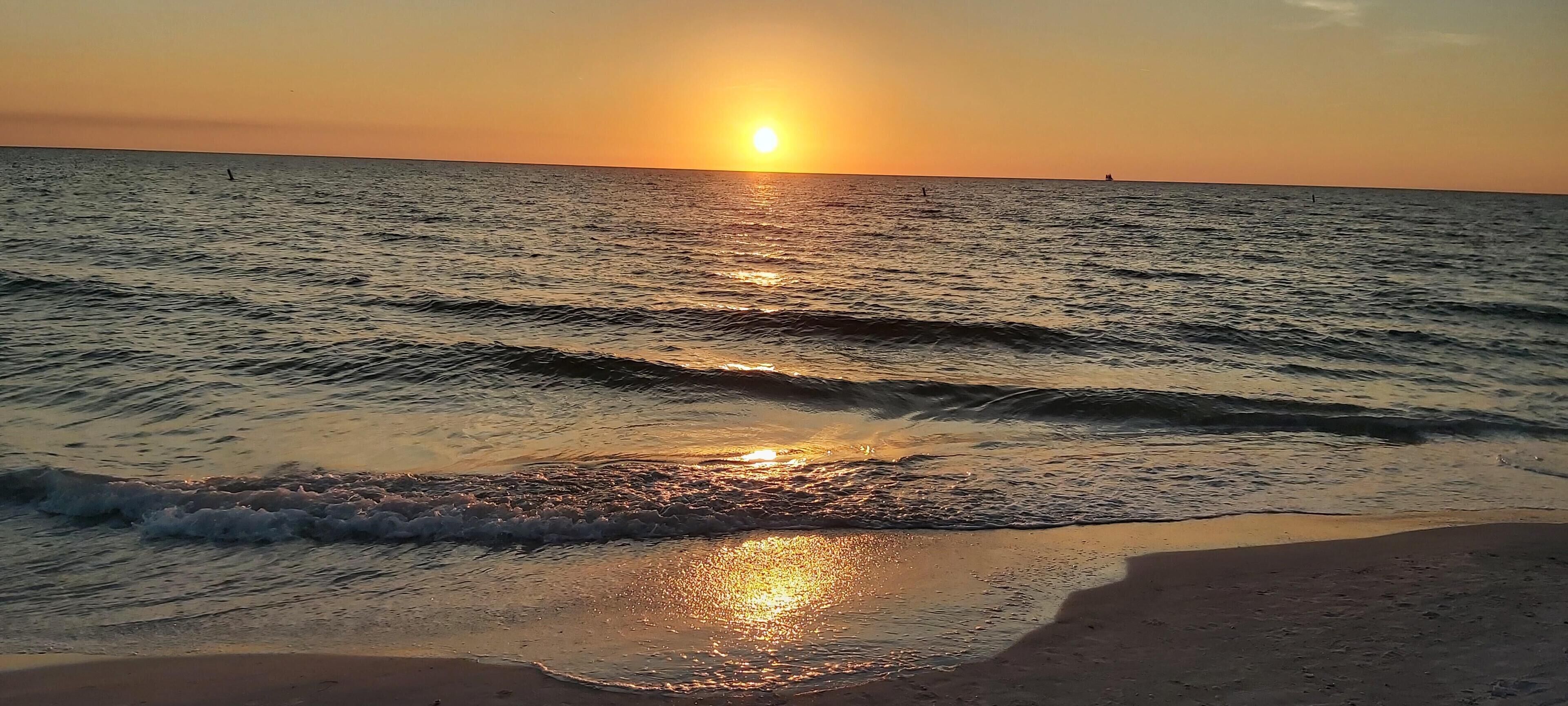 A sunset over a calm sea with gentle waves.
