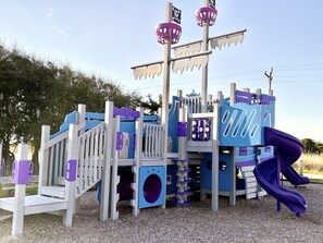 Un parc infantil amb tobogan, elements per escalar i decoració amb temàtica pirata.