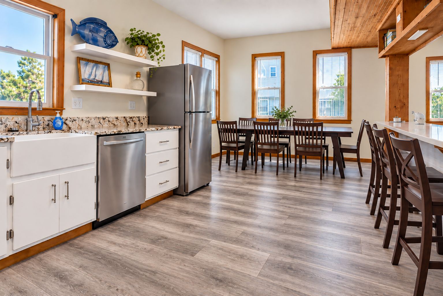 A modern kitchen with a dishwasher, refrigerator, and wooden dining table with chairs.