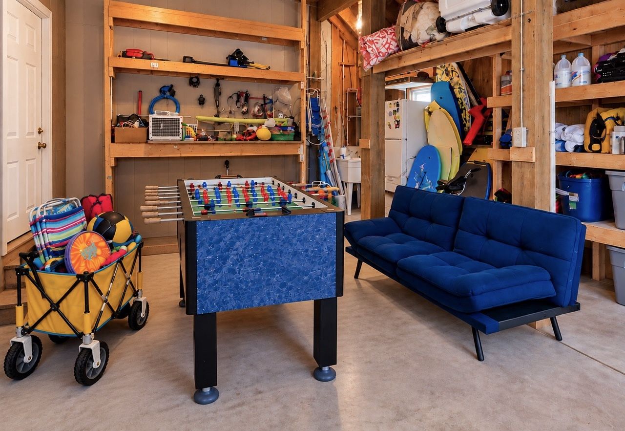 A room with a foosball table, a blue sofa, and a stroller with toys.