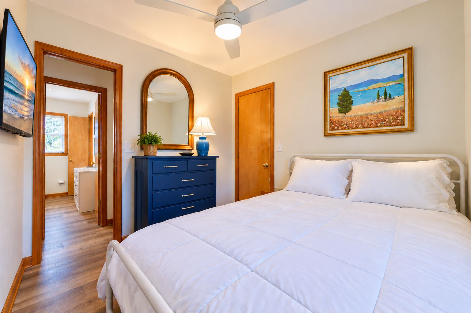 Un dormitorio con una cama grande, un aparador, un espejo y un cuadro en la pared.