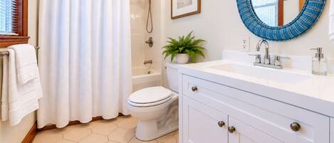 A bathroom with a shower, toilet, sink, and a step stool.
