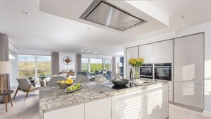Een moderne keuken met een groot schiereiland, inbouwapparatuur en uitzicht op de omgeving.