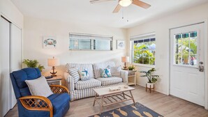 A living room with a blue sofa, a striped sofa, a wooden coffee table, and a ceiling fan. - Beach Quarters #2 (Gulfport)