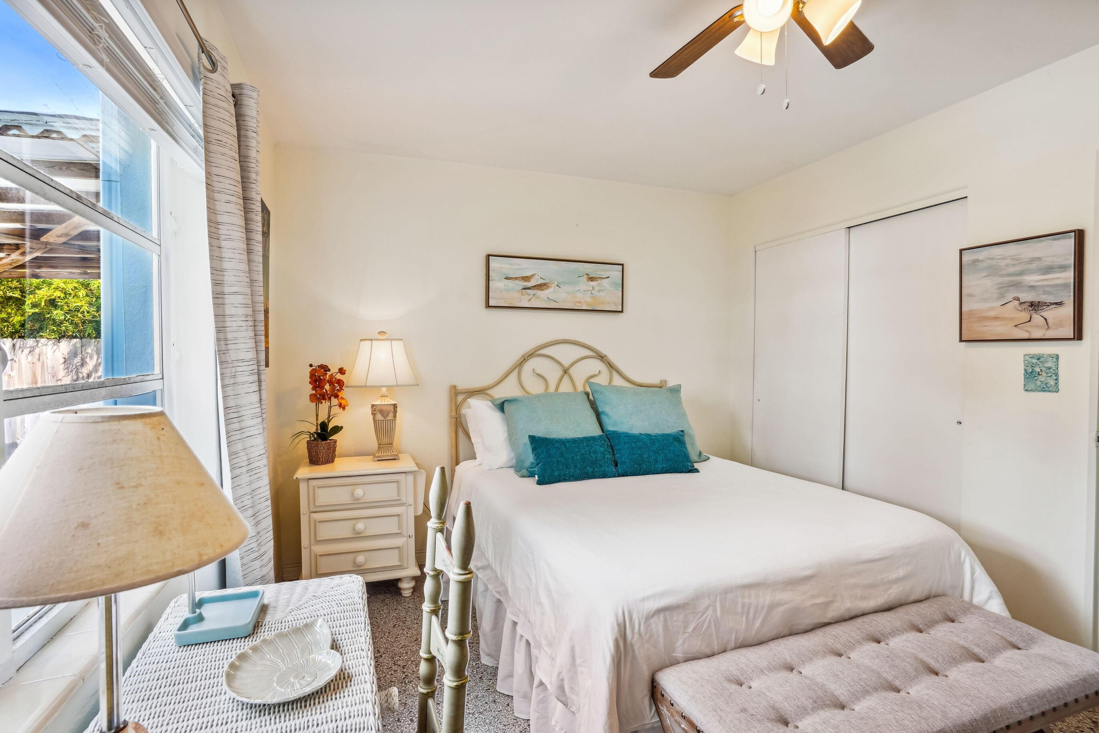 A bedroom with a bed, bedside table, lamp, and a window with curtains.