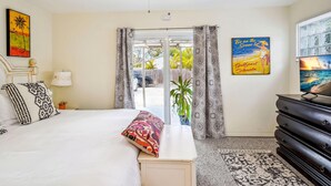 Ein Schlafzimmer mit Bett, Deckenventilator, Kommode und einem Fenster mit Vorhängen.