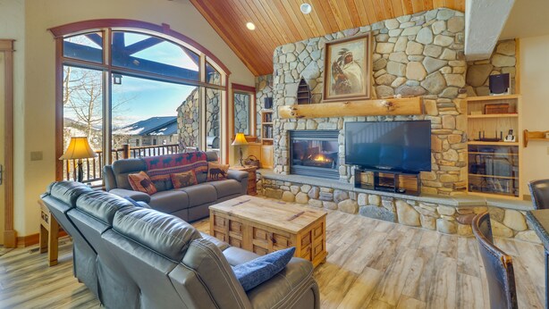 Amplia sala de estar con chimenea de piedra, sofá de cuero y televisor.