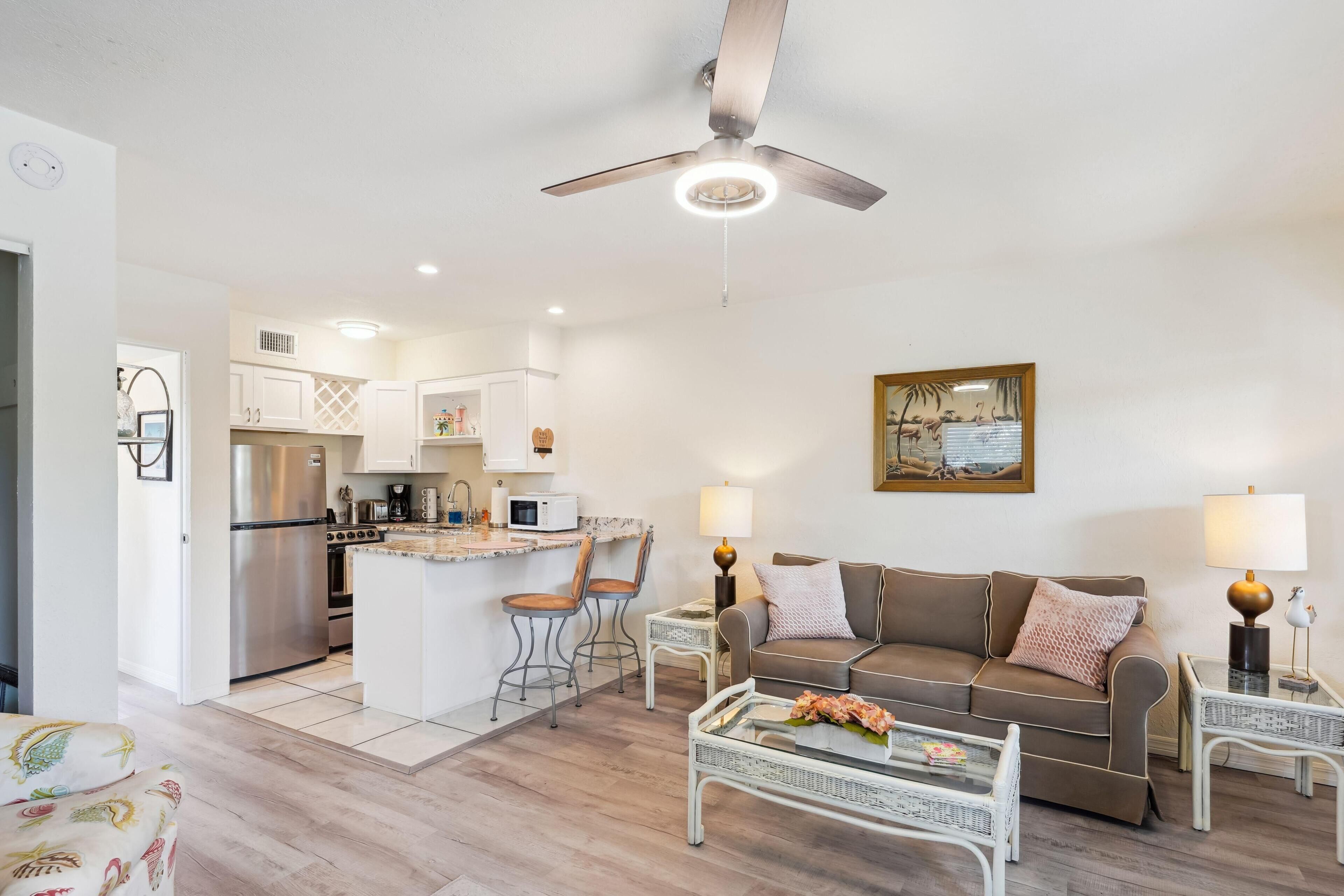 A modern kitchen with white cabinets, a stainless steel refrigerator, and a central island with bar stools.