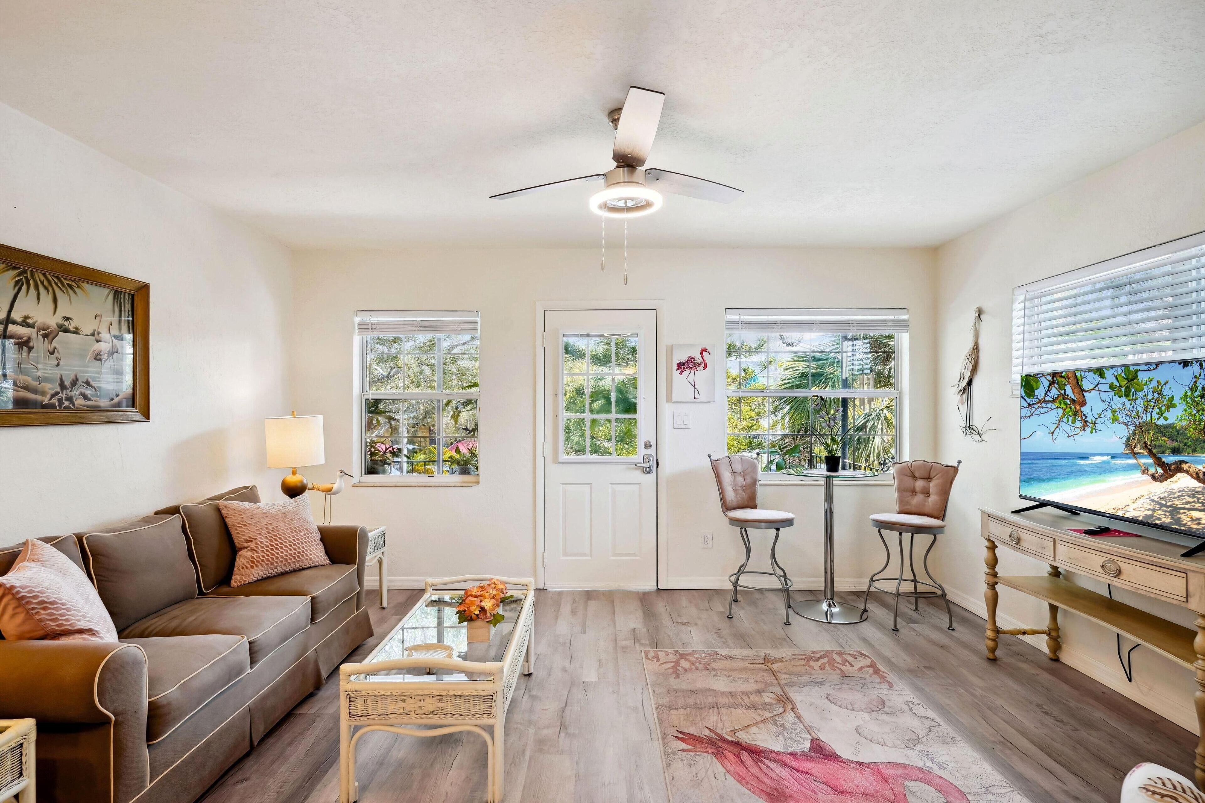 A living room with a brown sofa, a glass coffee table, a TV, and a ceiling fan.