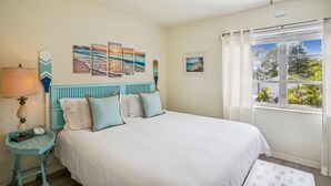 A bedroom with a bed, a nightstand, a ceiling fan, and a window with curtains. - Beach Quarters #8 (Gulfport)