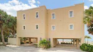 A two-story building with a flat roof, multiple windows, and a covered parking area.