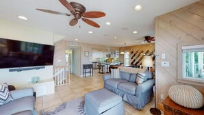 A spacious living area with a flat-screen TV, a ceiling fan, and a cozy seating arrangement.