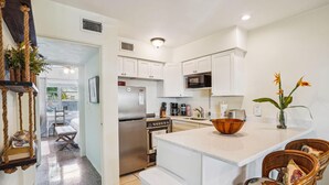 A modern kitchen with white cabinets, stainless steel appliances, and a central island with seating. - Beach Quarters 3BR - #2, #3, #4 (Gulfport)