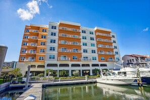 A multi-story hotel with balconies, a marina with boats, and a clear blue sky. - Madeira Bay Resort I 1408 (Madeira Beach)