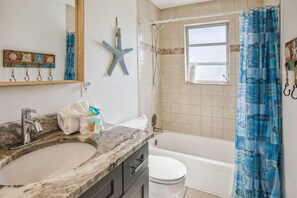 A bathroom with a marble sink, a white toilet, a bathtub, and a shower with a glass door. - Beach Life 3 (Treasure Island)