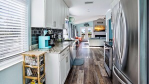A kitchen with a stainless steel refrigerator, wooden cabinets, and a blue countertop. - Beach Life 5 (Treasure Island)