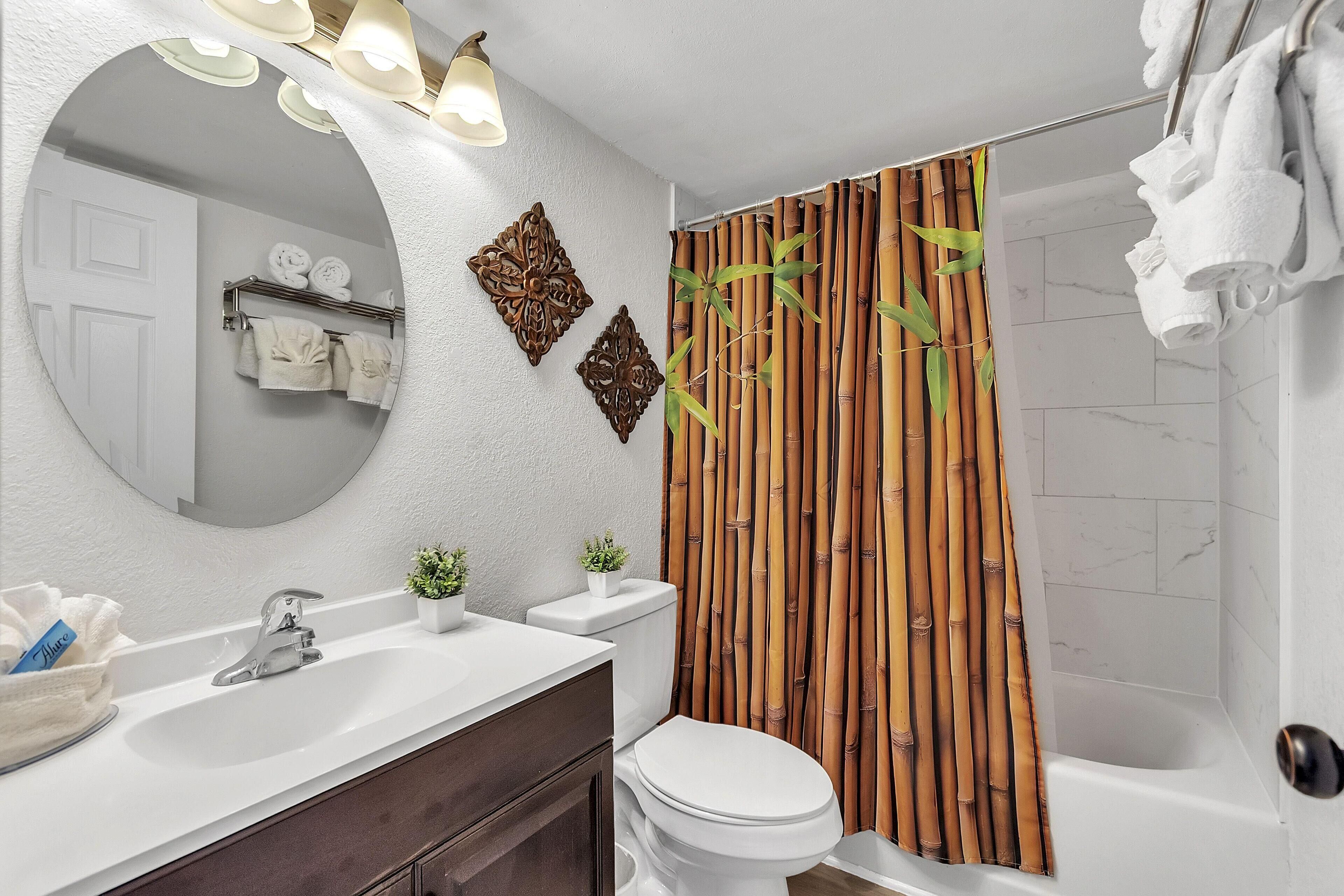 A bathroom with a white sink, a toilet, and a shower area. There are decorative wall panels and a mirror above the sink.