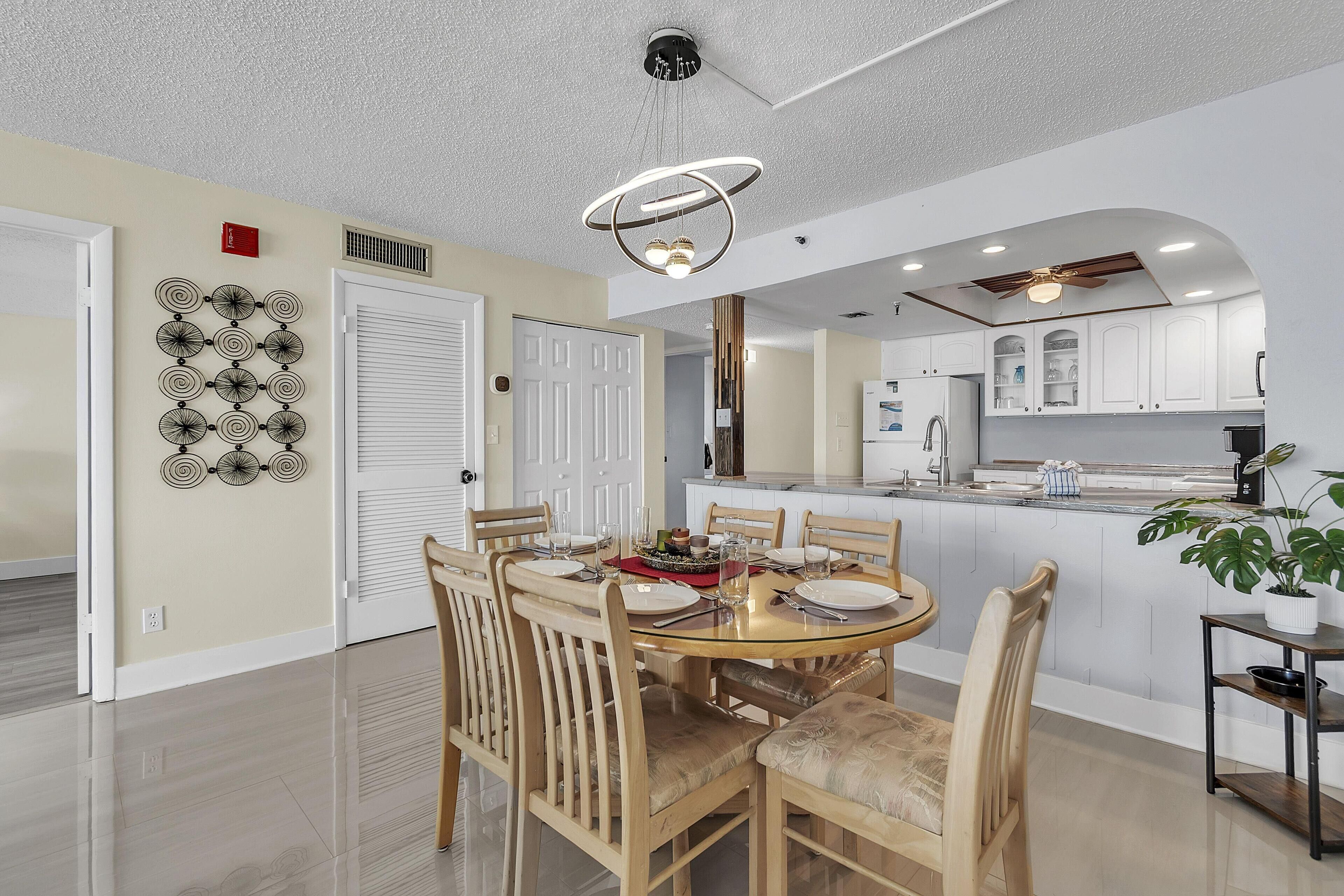 Una cocina moderna con armarios blancos, una isla central y un comedor con mesa y sillas redondas.