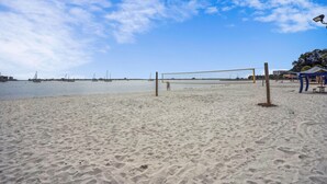 A sandy beach with a volleyball net, a small pavilion, and a clear sky. - Beach Quarters 2BR #5 and #6 (Gulfport)