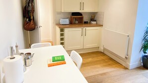 Una cocina compacta con armarios blancos, una encimera de madera y una mesa de comedor con sillas.