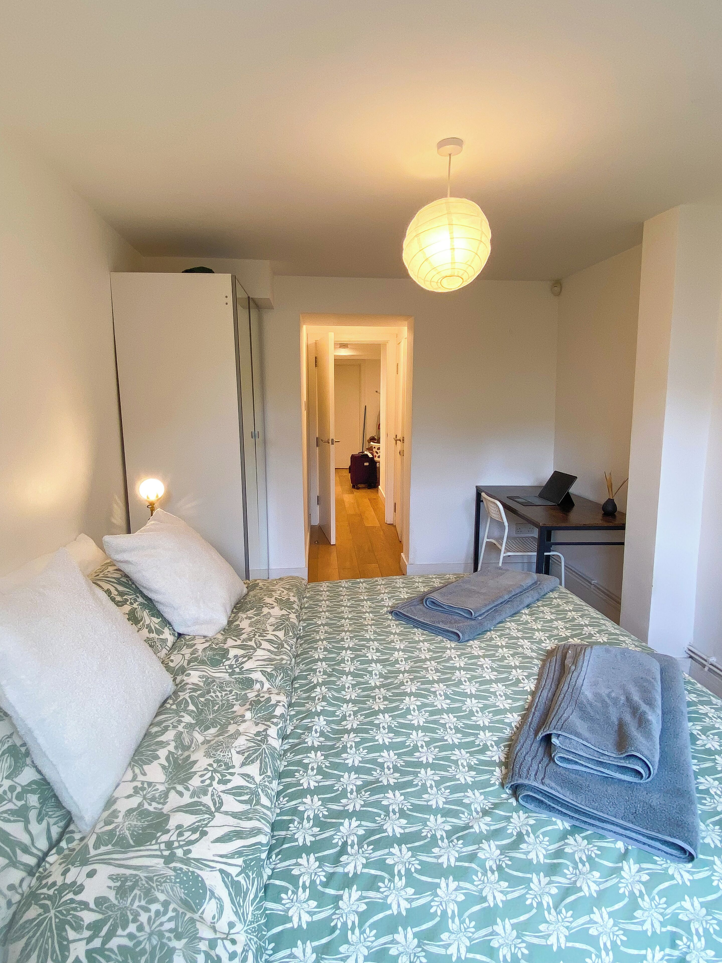 A bedroom with a bed, a desk, and a chair.