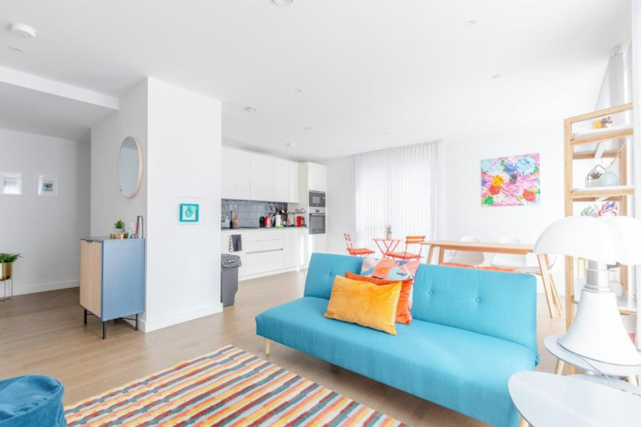 A modern living room with a sofa, a dining table, and a kitchen in the background.